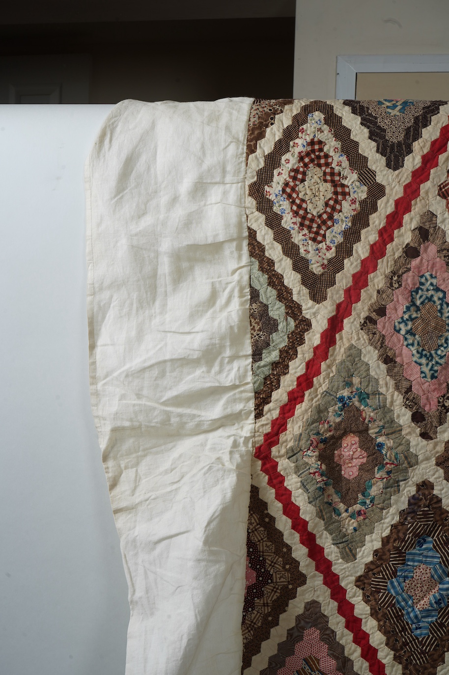 An ornate 19th century Log Cabin patchwork, made mostly from printed dress cottons from 1850-1900. 195cm long x 157cm wide., Condition - The colours are still bright and cotton strong. The patchwork backing and the cream